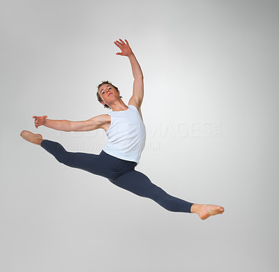 Ballet dancer practicing high jump against white background