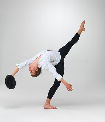 Male ballet dancer performing a unique step with hat in hand
