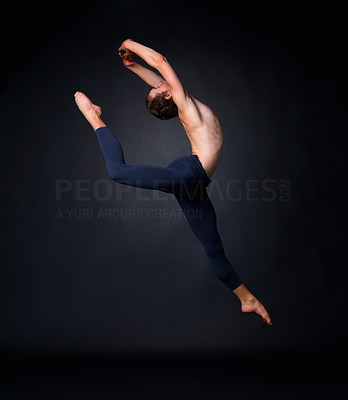 Young graceful ballet dancer leaping against black background