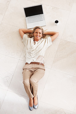Smiling woman lying on floor by laptop and tea cup