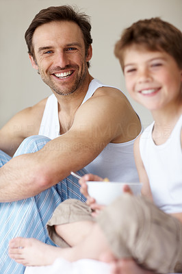 Happy young father sitting with his son eating breakfast