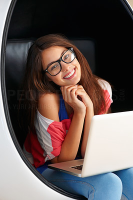 Cute girl sitting on egg chair using laptop