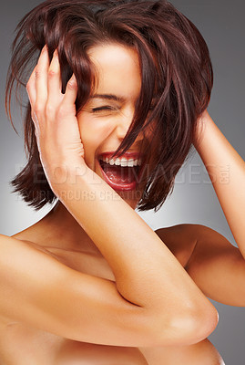 Joyful nude woman laughing against colored background