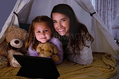 Buy stock photo Shot of a little girl and her mother watching something on a digital tablet at night
