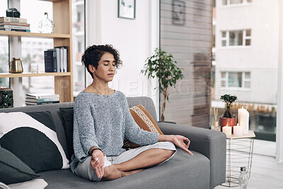 Buy stock photo Shot of an attractive young woman meditating on a sofa at home