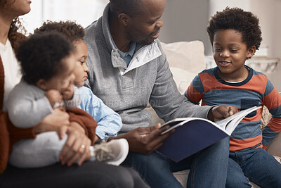 Buy stock photo Shot of a father reading a book to his family at home