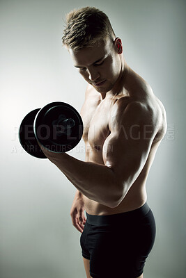 Buy stock photo Studio shot of a muscular young man exercising with a dumbbell against a grey background