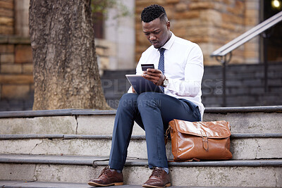 Buy stock photo Shot of a young businessman using a credit card and digital tablet in the city