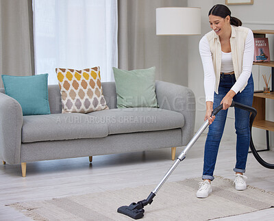 Buy stock photo Shot of a young woman vacuuming the carpet in her home