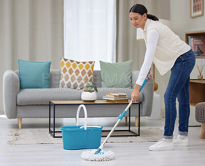 Buy stock photo Shot of a young woman mopping her living room floors