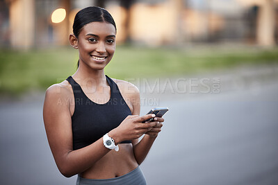 Buy stock photo Portrait of a sporty young woman using a cellphone while exercising outdoors