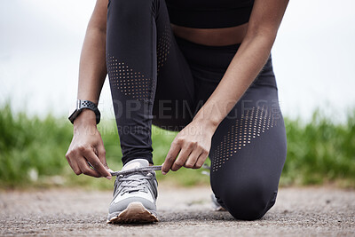 Buy stock photo Closeup shot of an unrecognisable woman tying her shoelaces while exercising outdoors