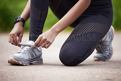 Buy stock photo Closeup shot of an unrecognisable woman tying her shoelaces while exercising outdoors