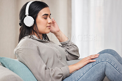 Buy stock photo Shot of a young woman listening to music wearing headphones at home