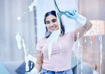 Buy stock photo Shot of a young woman cleaning windows at home