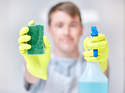 Buy stock photo Shot of a young man holding a spray bottle of detergent and a sponge
