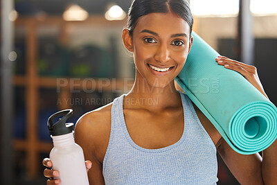 Buy stock photo Portrait of a fit young woman holding an exercise mat and water bottle in a gym