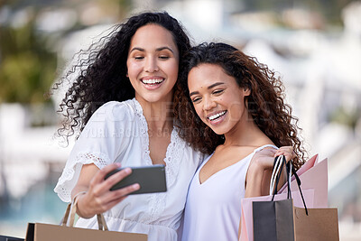 Buy stock photo Shot of two young women taking selfies while shopping against an urban background