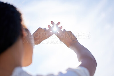 Buy stock photo Low angle shot of a woman holding her hands up to a sunny sky and making hand gestures