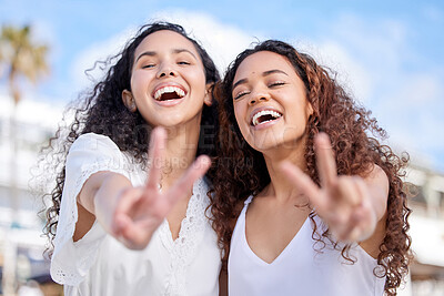 Buy stock photo Shot of two young women making peace gestures during a fun day outdoors