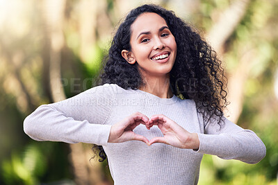Buy stock photo Shot of a young woman making a heart shaped gesture while enjoying a day out in nature