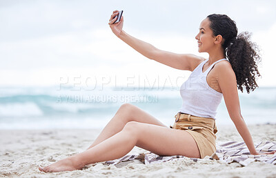 Buy stock photo Shot of a young woman taking a selfie at the beach