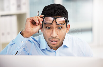 Buy stock photo Shot of a young businessman looking shocked while working at his desk