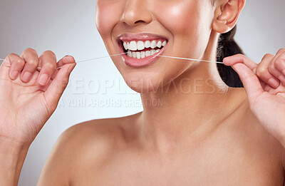 Buy stock photo Studio shot of a beautiful young woman flossing her teeth against a grey background