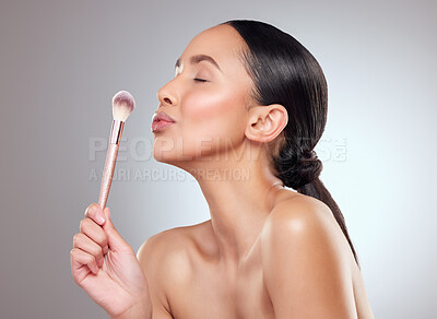 Buy stock photo Studio shot of a beautiful young woman applying makeup to her face with a brush against a grey background