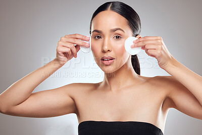 Buy stock photo Studio portrait of a beautiful young woman using a cotton pad on her face against a grey background