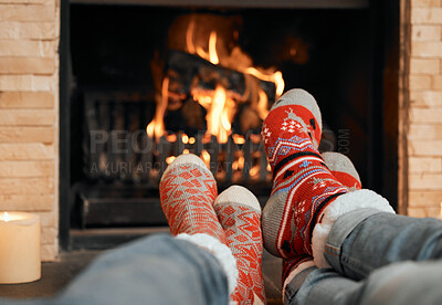 Buy stock photo Closeup shot of a couple wearing Christmas socks while relaxing with their feet up by a fireplace at home