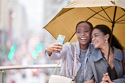 Buy stock photo Shot of two young friends taking a selfie in the rain