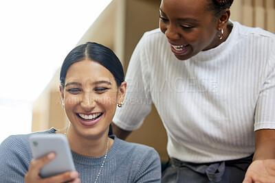 Buy stock photo Cropped shot of two attractive young businesswomen looking at a cellphone together in the office