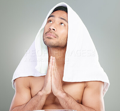 Buy stock photo Studio shot of a handsome young man praying while going through his morning grooming routine against a grey background