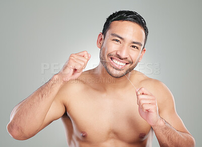 Buy stock photo Studio shot of a handsome young man flossing his teeth against a grey background