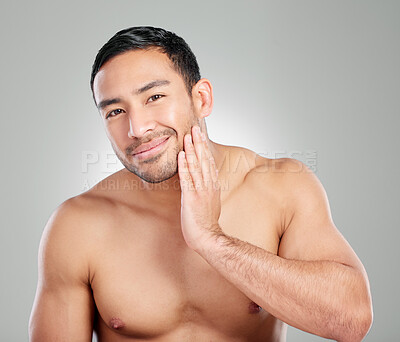 Buy stock photo Studio shot of a handsome young man touching his face against a grey background