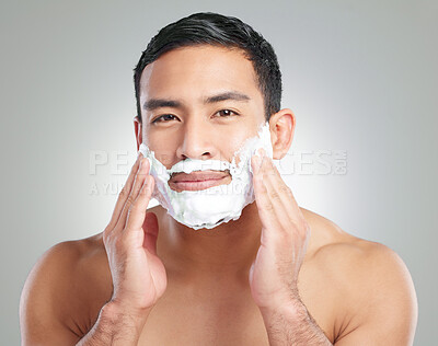 Buy stock photo Studio shot of a handsome young man shaving against a grey background