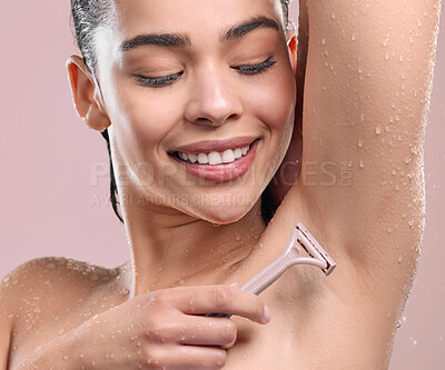 Buy stock photo Shot of a young woman shaving her armpits against a studio background