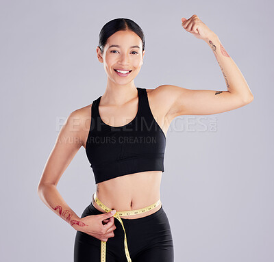 Buy stock photo Shot of an attractive young woman standing in the studio and using a measuring tape around her waist