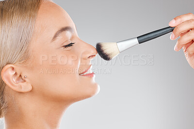 Buy stock photo Shot of an attractive young woman using a makeup brush against a studio background