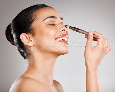 Buy stock photo Studio shot of an attractive young woman applying makeup against a grey background