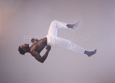 Buy stock photo Shot of a young man in mid air against a grey background
