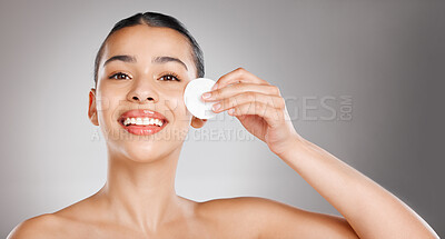 Buy stock photo Studio shot of an attractive young woman wiping her face with a cotton pad against a grey background