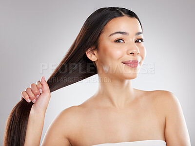 Buy stock photo Studio portrait of an attractive young woman holding her hair against a grey background