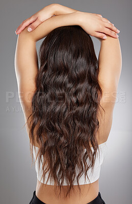 Buy stock photo Rearview shot of a young woman with long curly hair against a grey background