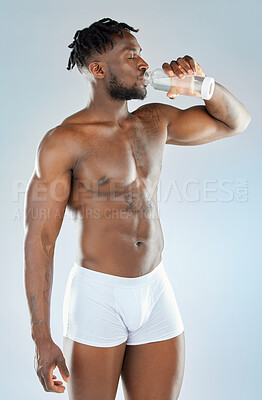 Buy stock photo Studio shot of a muscular young man drinking a glass of water