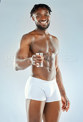 Buy stock photo Studio shot of a muscular young man holding out a glass of water