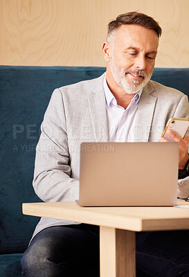 Buy stock photo Cropped shot of a handsome mature businessman checking his messages while working on his laptop in the office