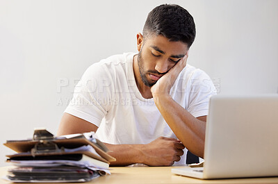 Buy stock photo Shot of a handsome young man sitting alone and falling asleep while working from home