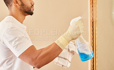 Buy stock photo Cropped shot of an unrecognisable man using a spray bottle and a cloth to clean his mirrors at home
